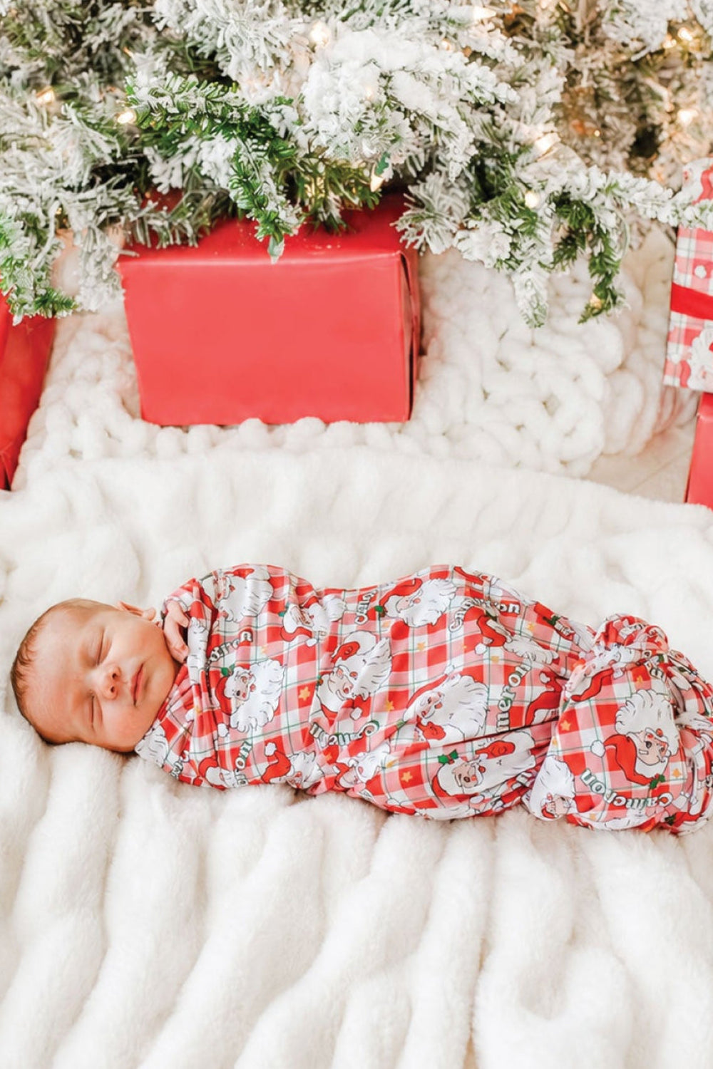 Sleeping newborn wrapped in a personalized Cozy Claus bamboo swaddle blanket with vintage Santa print, perfect for Christmas baby announcements and holiday keepsake photos.