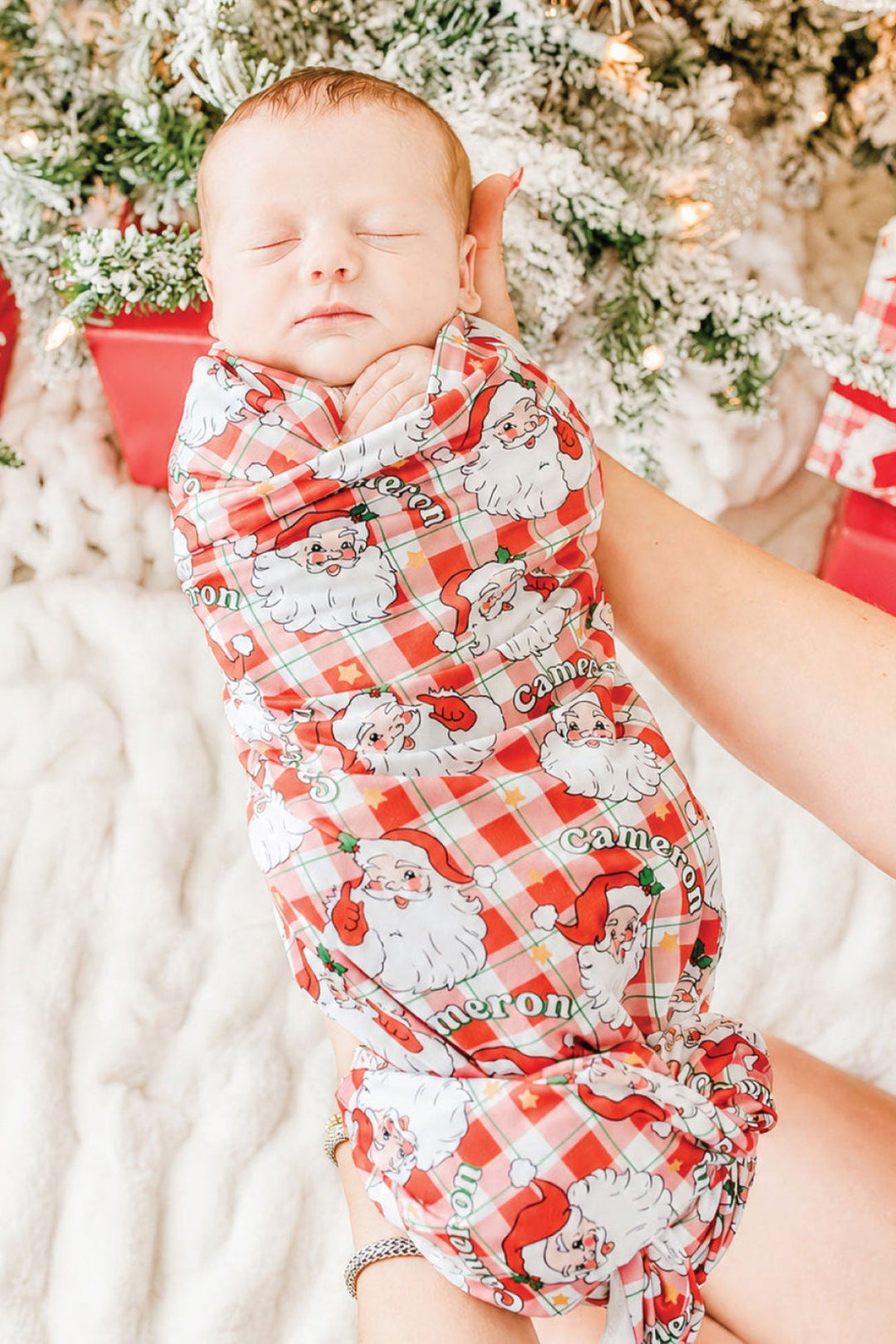 Personalized Cozy Claus Christmas bamboo swaddle blanket featuring a vintage Santa print, wrapped around a sleeping newborn for Christmas newborn photos and personalized baby gifts.