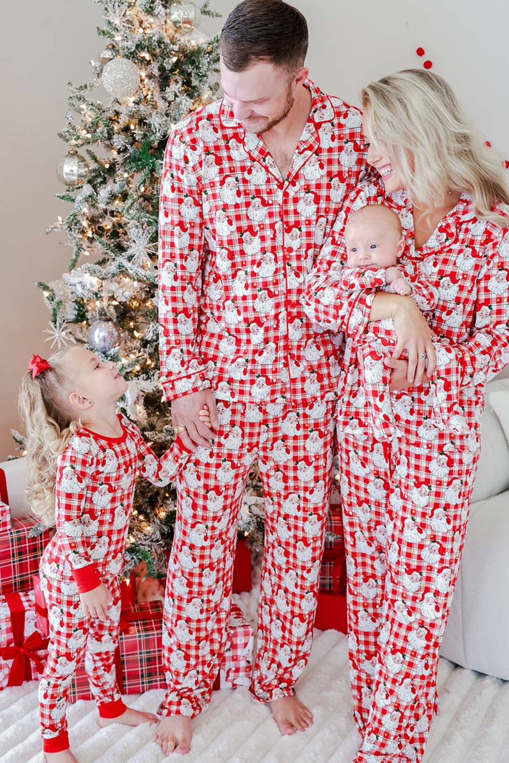Family wearing Caden Lane Cozy Claus matching Christmas pajamas featuring vintage Santa plaid prints for parents, baby, and toddler on Christmas morning.