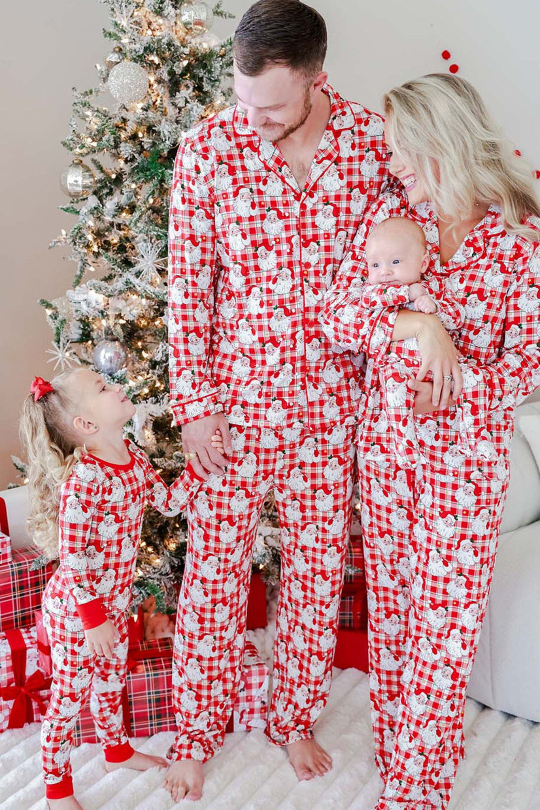 Family wearing Caden Lane Cozy Claus matching Christmas pajamas featuring vintage Santa plaid prints for parents, baby, and toddler on Christmas morning.
