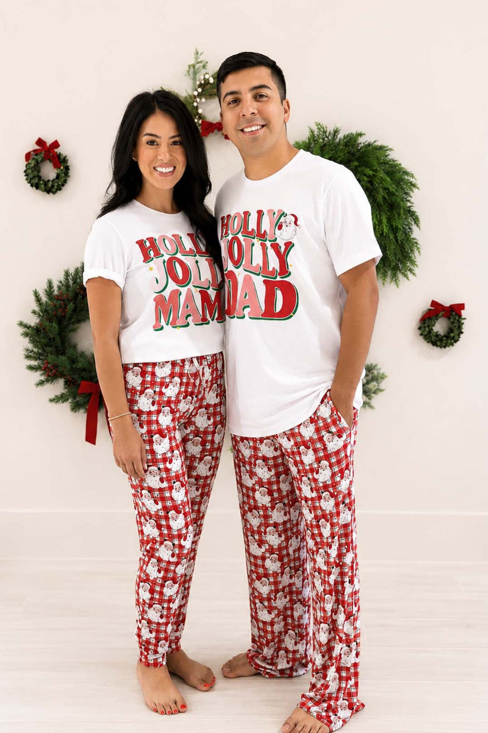 Couple wearing Caden Lane Cozy Claus matching Christmas pajama pants with coordinating holiday graphic tees, perfect for festive family pajamas and Christmas morning traditions.