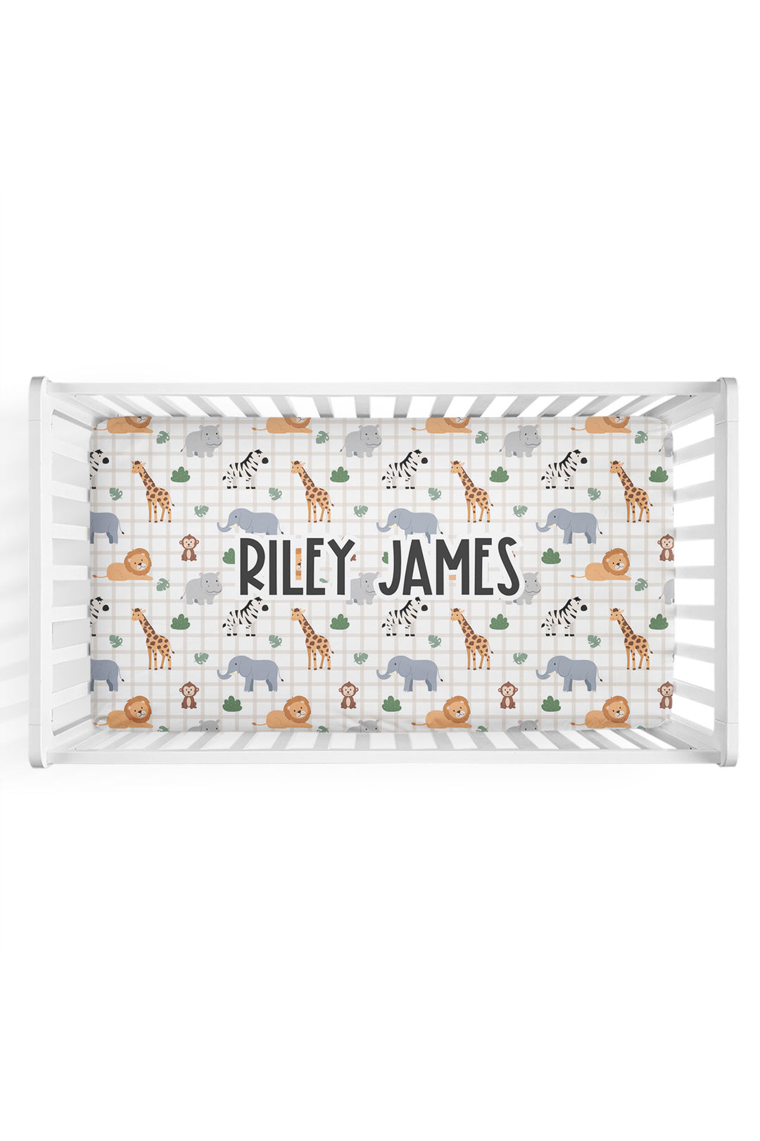 Overhead view of a white crib fitted with a Caden Lane personalized crib sheet in a Wild Child print featuring safari animals on cream plaid, with a large name reading "Riley James."