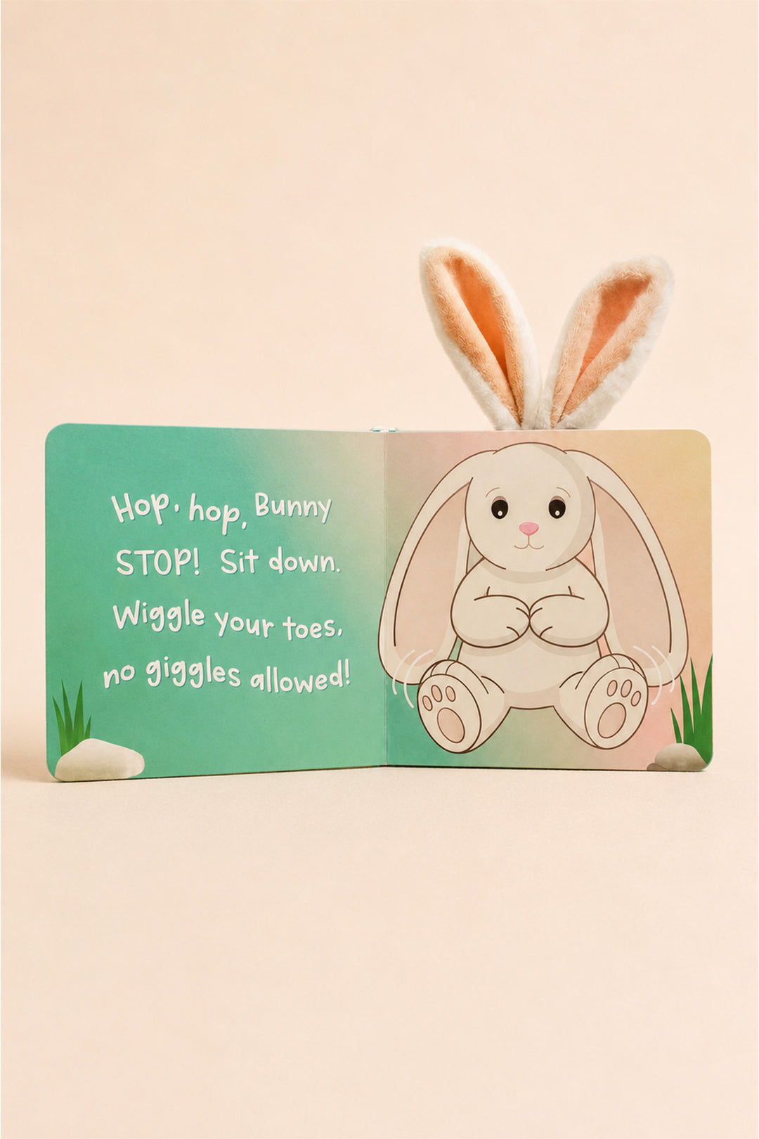 A children's pop-up book featuring a bunny pop-up with long ears popping up from the cover. The open book shows a turquoise left page with text reading 'Hop, hop, Bunny STOP! Sit down.