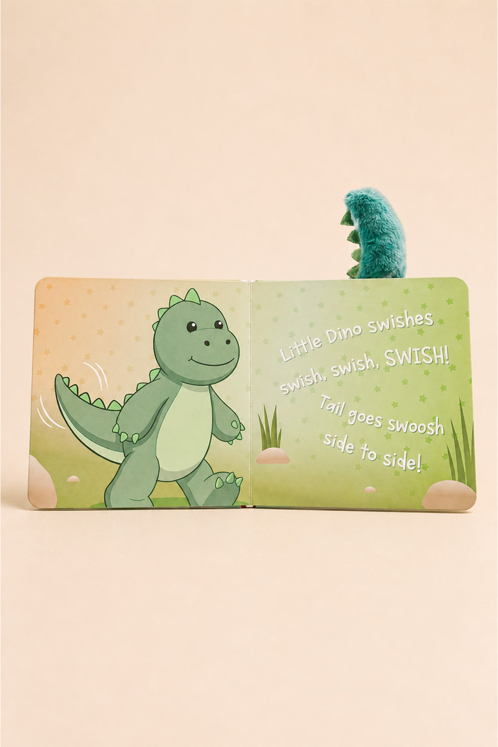 A children's pop-up book featuring a cute green cartoon dinosaur on the left page and playful text on the right page, with a plush green dinosaur tail popping up from the top right against a warm beige background.