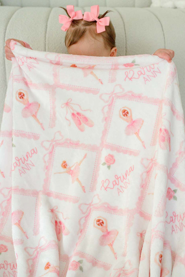 Baby girl sitting with a matching personalized plush blanket embroidered with her name
