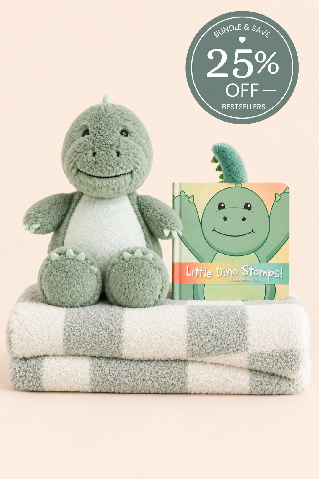 A Caden Lane plush green dinosaur seated on a folded sage-and-cream striped blanket, paired with a "Little Dino Stomps!" board book.