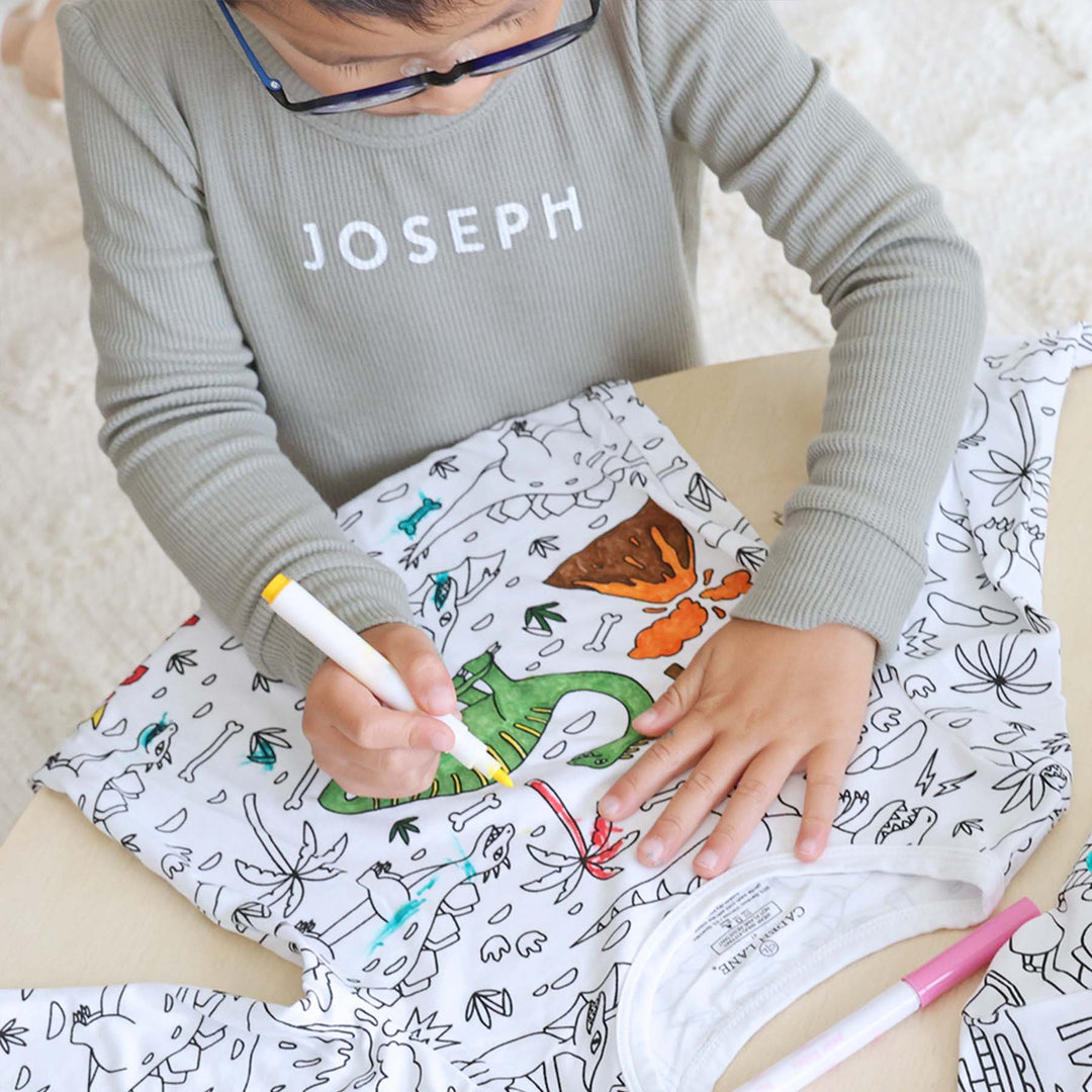 boy coloring the Jurassic Playground Colorable Pajama Two Piece Set