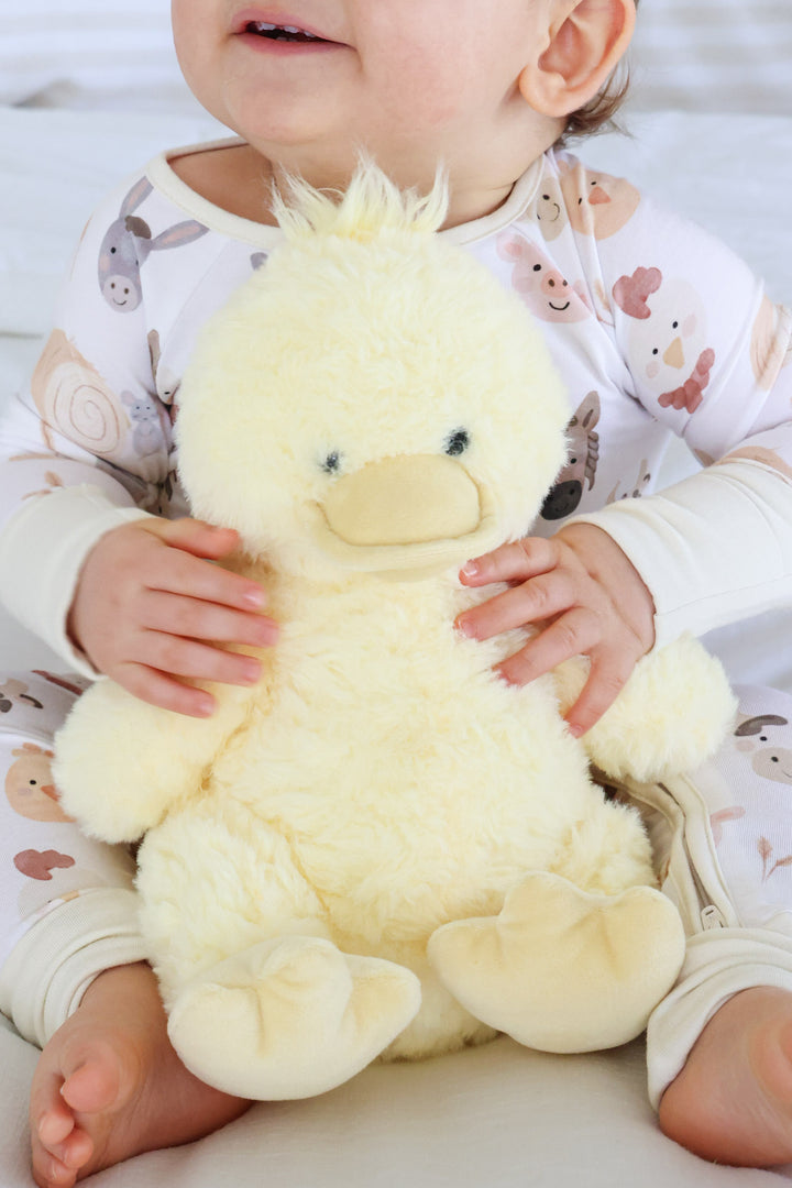 baby boy holding a duck stuffed animal in his lap 