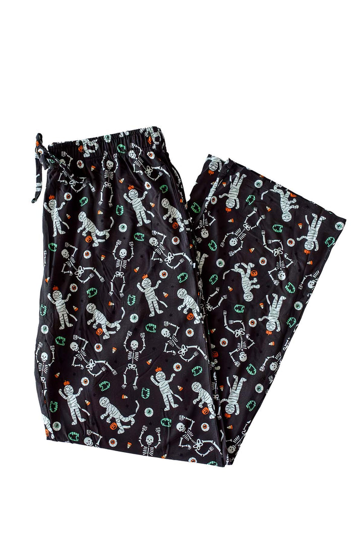 Black pajama pants with an all-over glow-in-the-dark skeleton and mummy print with candy corn accents, featuring a drawstring waistband.