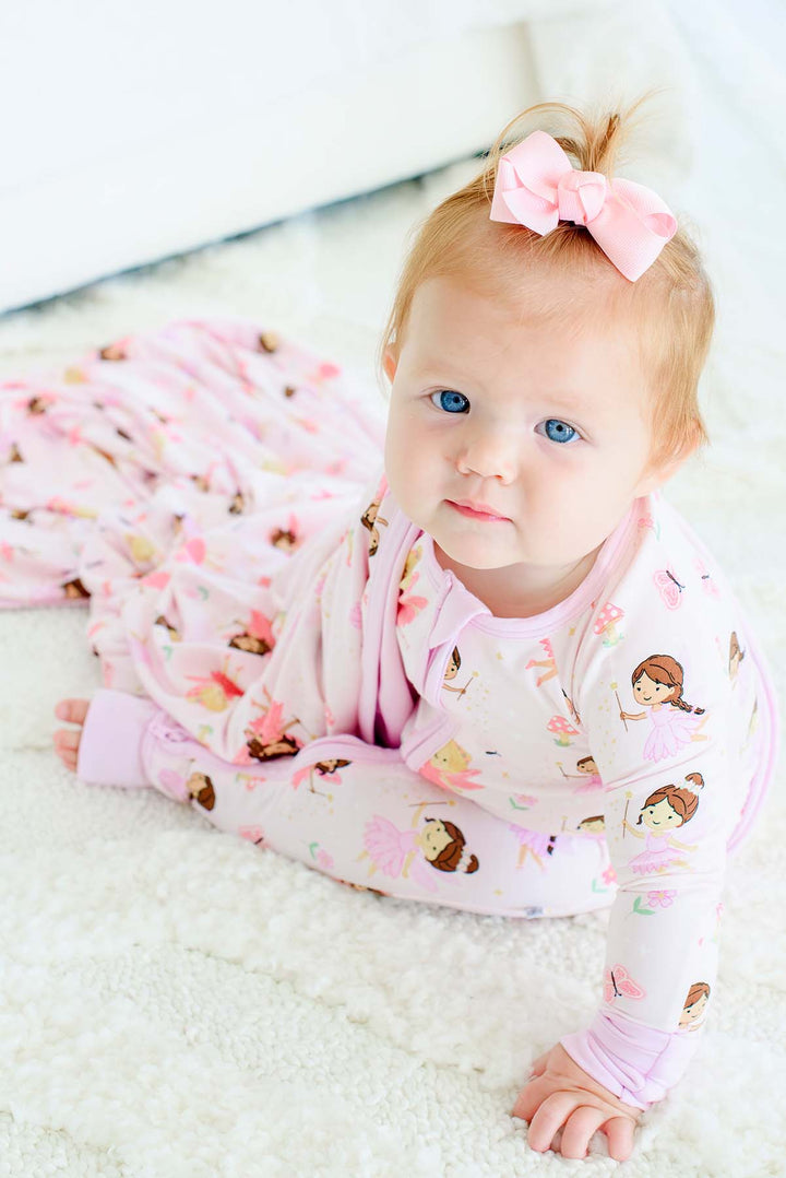 Baby girl with a pink bow crawling on a rug in the Fairy Wishes glow-in-the-dark convertible bamboo zip romper