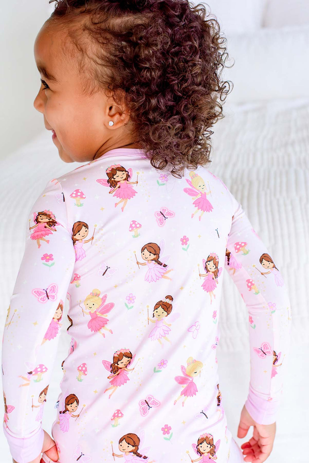 Back view of a toddler in the Fairy Wishes glow-in-the-dark two-piece bamboo pajama top showing the fairy and butterfly print