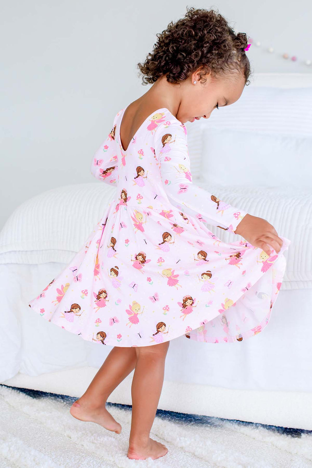 Side view of a toddler twirling in the Fairy Wishes long sleeve twirl dress, showing the scoop back and full skirt