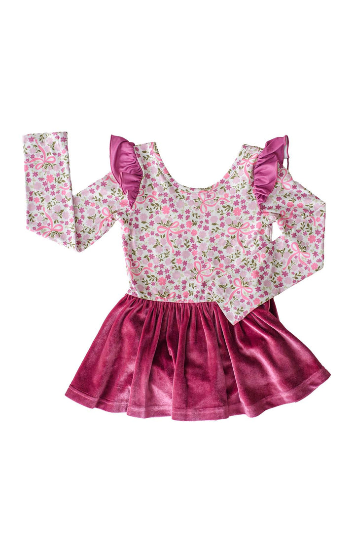 Flat lay of a Caden Lane long-sleeve leotard in a pink floral and bow print with berry flutter sleeves and an attached berry velvet skirt.