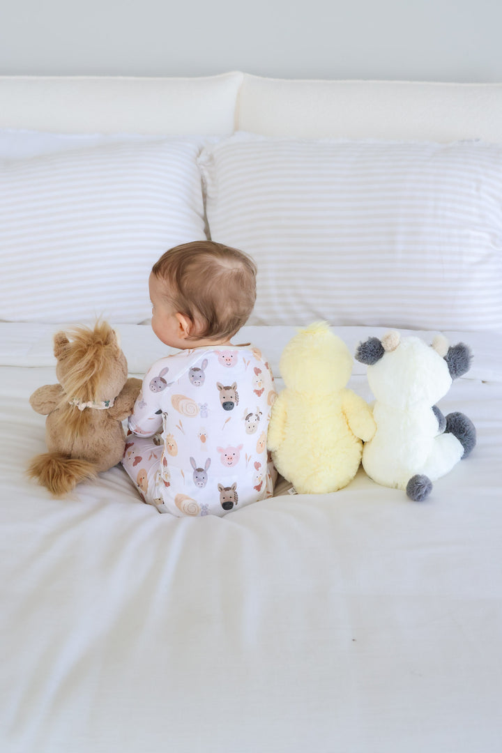 back view of farm stuffed animals with a boy wearing a farm pajama romper 