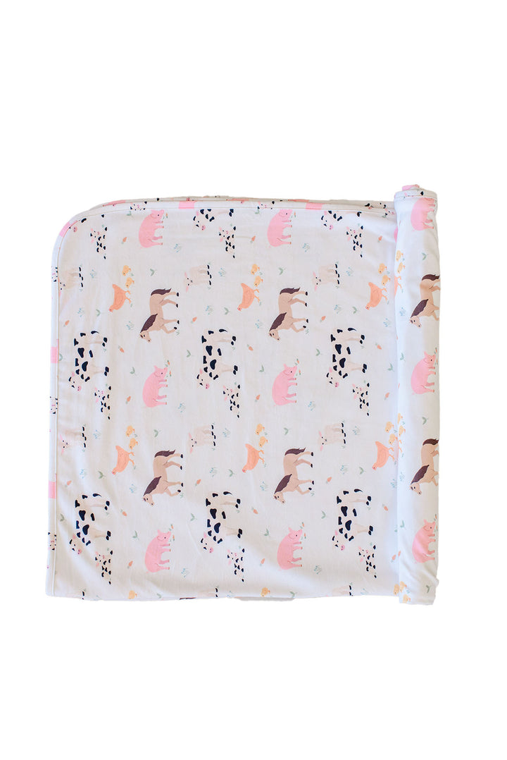 Caden Lane farm animal swaddle blanket folded flat with pink trim, featuring cow, horse, pig, and chicken print