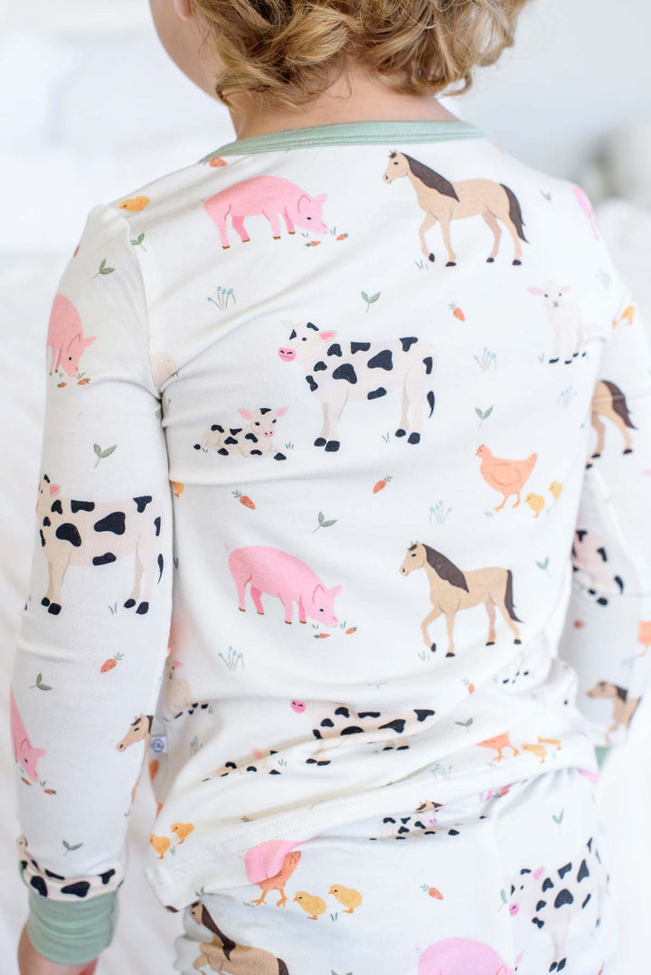Close-up back view of Caden Lane farm animal pajama set showing cow, horse, pig, and chicken print with sage trim