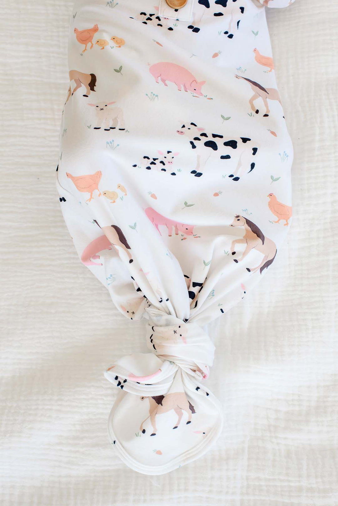 Close-up of knotted hem on Caden Lane farm animal newborn gown with cow, pig, horse, and chicken print
