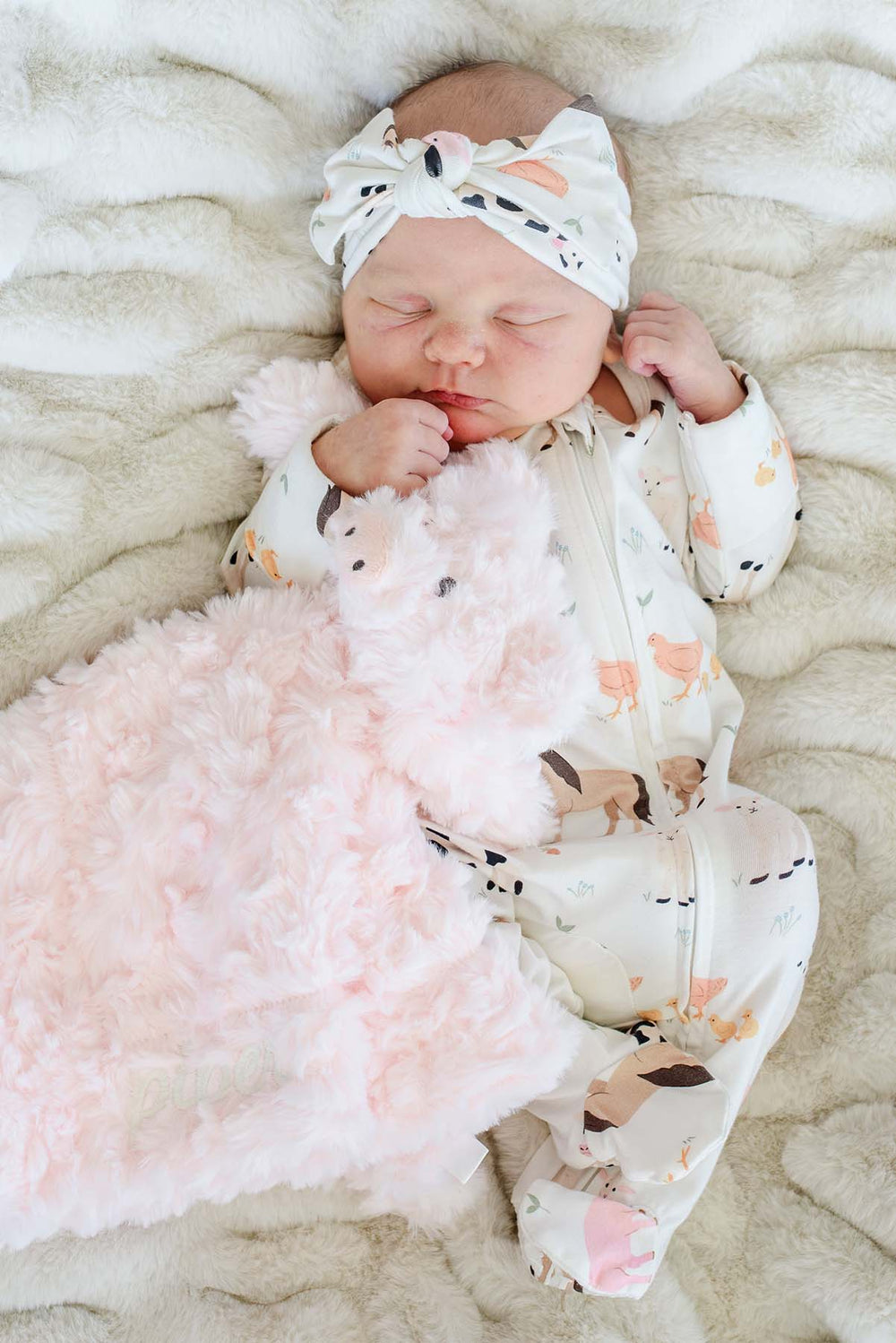 Sleeping baby in a farm print sleeper cuddling a blush Caden Lane pig lovey with tone-on-tone name embroidery