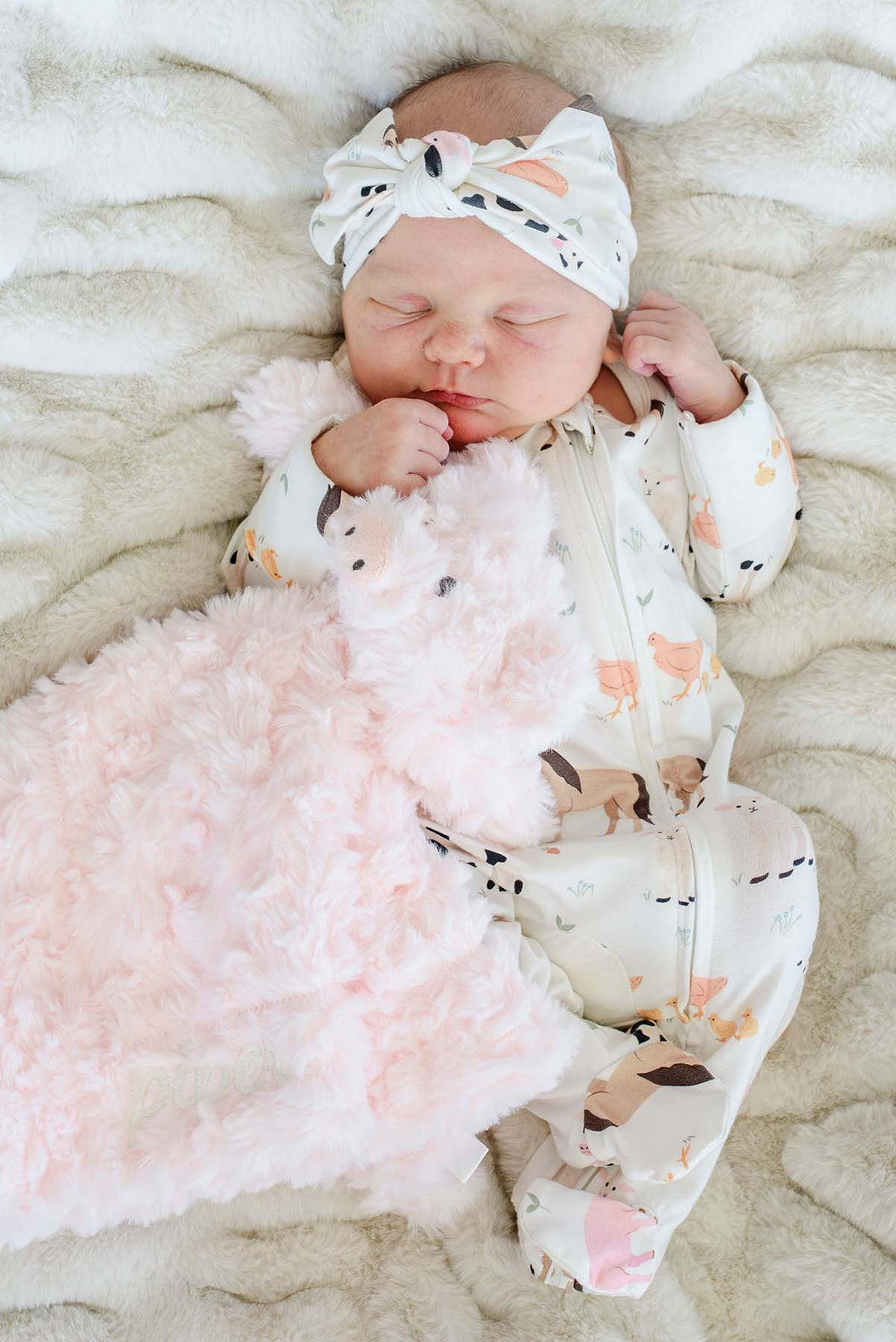 Sleeping baby in a farm print sleeper cuddling a blush Caden Lane pig lovey with tone-on-tone name embroidery