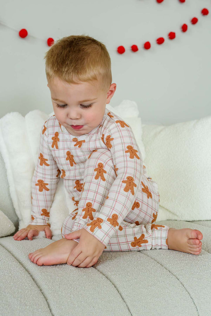 child kneeling by a christmas tree wearing a Caden Lane gingersnap bamboo waffle two-piece pajama set .