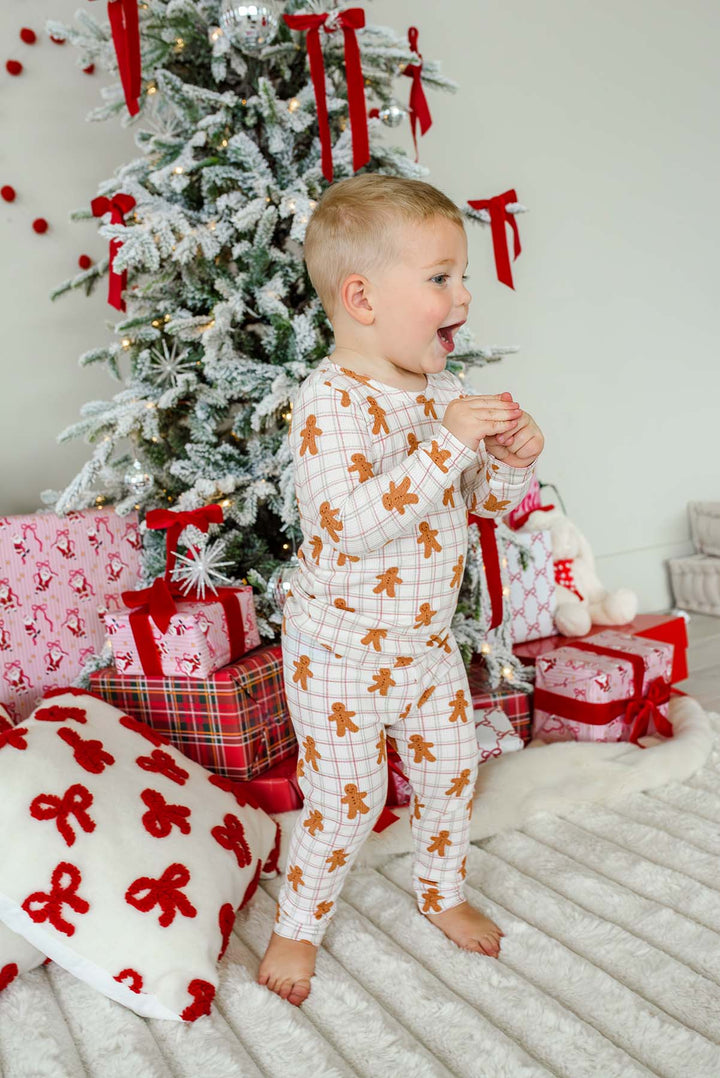 child kneeling by a christmas tree wearing a Caden Lane gingersnap bamboo waffle two-piece pajama set next to wrapped gifts