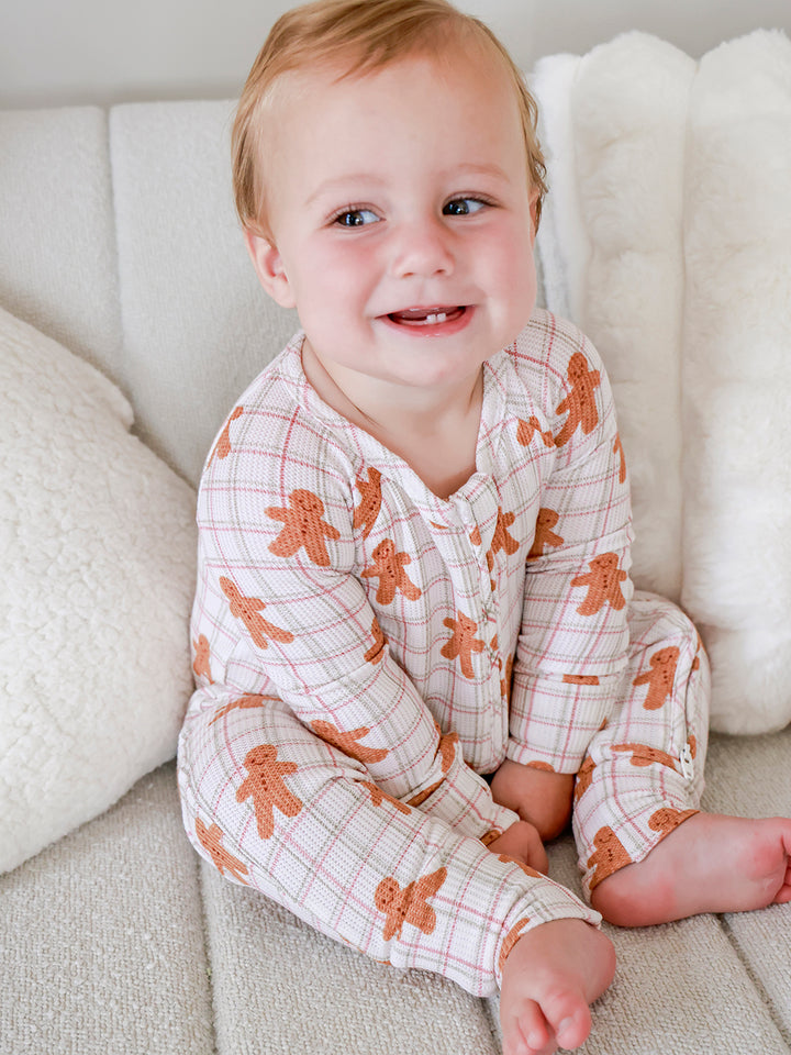 Toddler smiling in the Caden Lane Gingersnap Bamboo Waffle Convertible Zipper Romper, showcasing the gingerbread holiday print, breathable bamboo viscose waffle fabric, and cozy Christmas baby sleepwear.