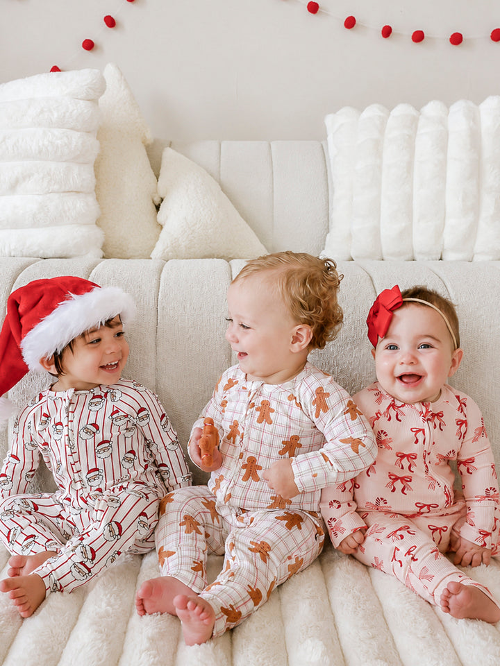 Three babies wearing Caden Lane matching bamboo waffle convertible zipper rompers from the Holly & Jolly, Gingersnap, and Peppermint Bows Christmas collections, perfect for coordinating sibling holiday pajamas and festive family photos.