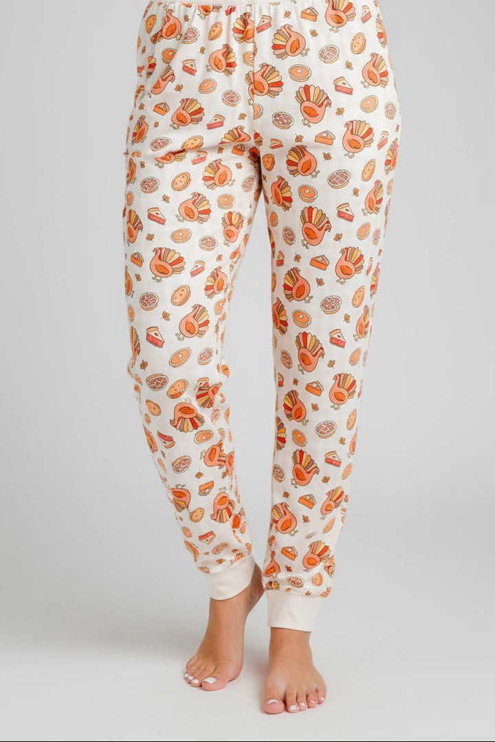 Close-up of a woman's legs wearing Caden Lane's turkey and pie print pajama pants with elastic cuffs.