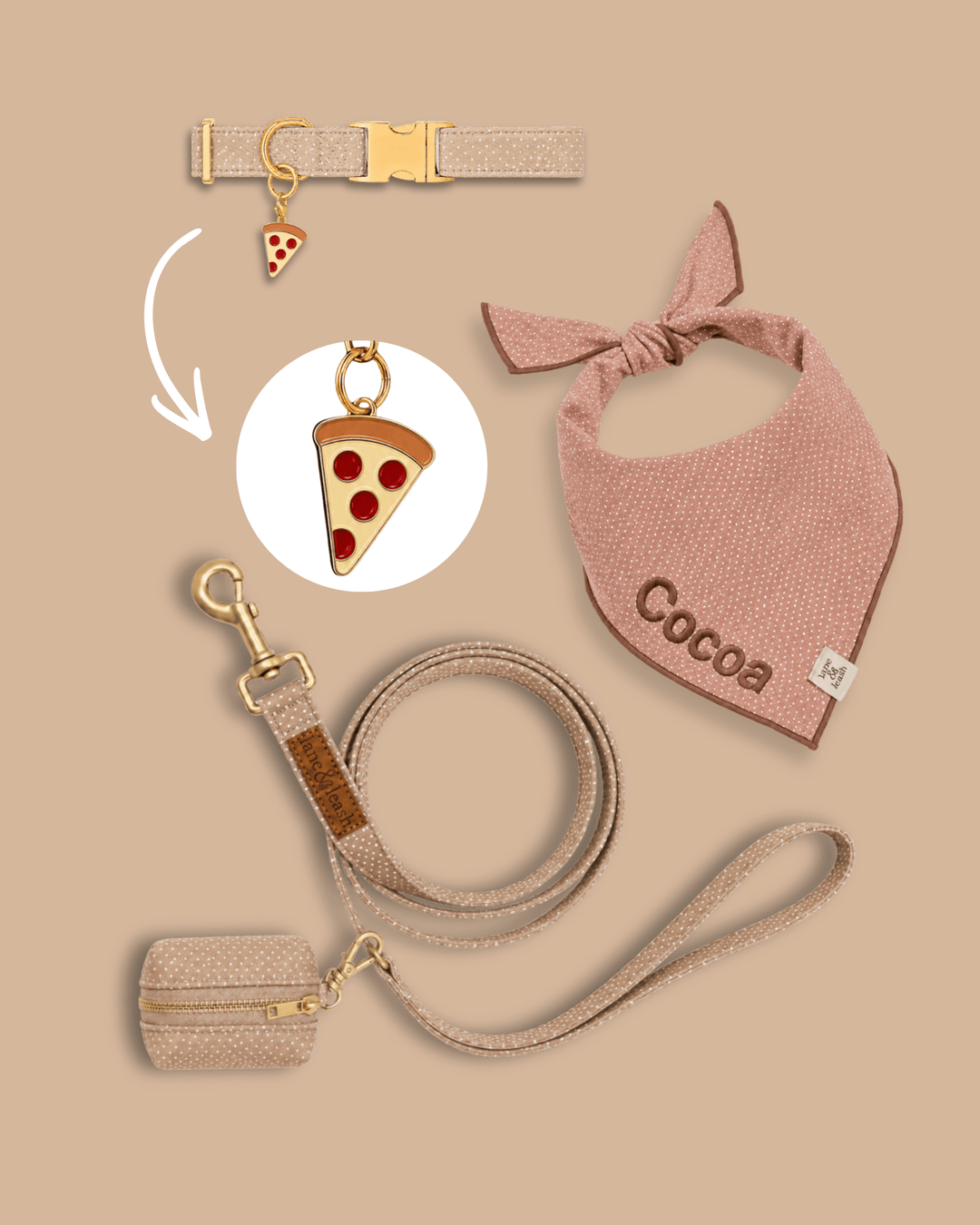 Neutral tan pet accessories flatlay on tan background with collar, bandana, leash, and poop bag holder, featuring a pizza slice charm highlighted in a circle callout