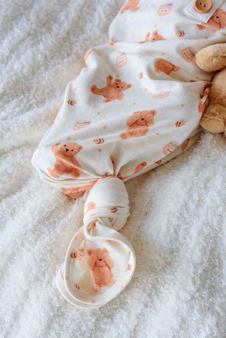 Newborn wearing a Caden Lane honey bear print knotted gown