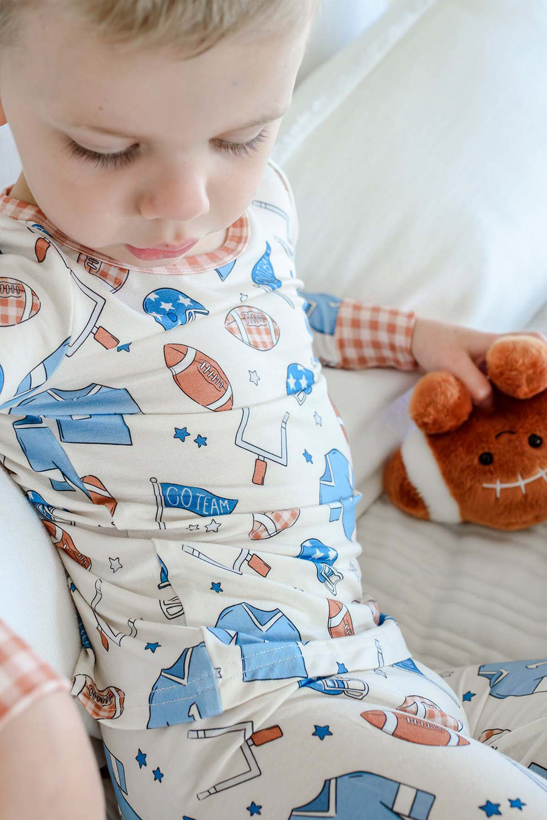 Close up of a little boy wearing the Caden Lane blue huddles and cuddles two piece pajama set.