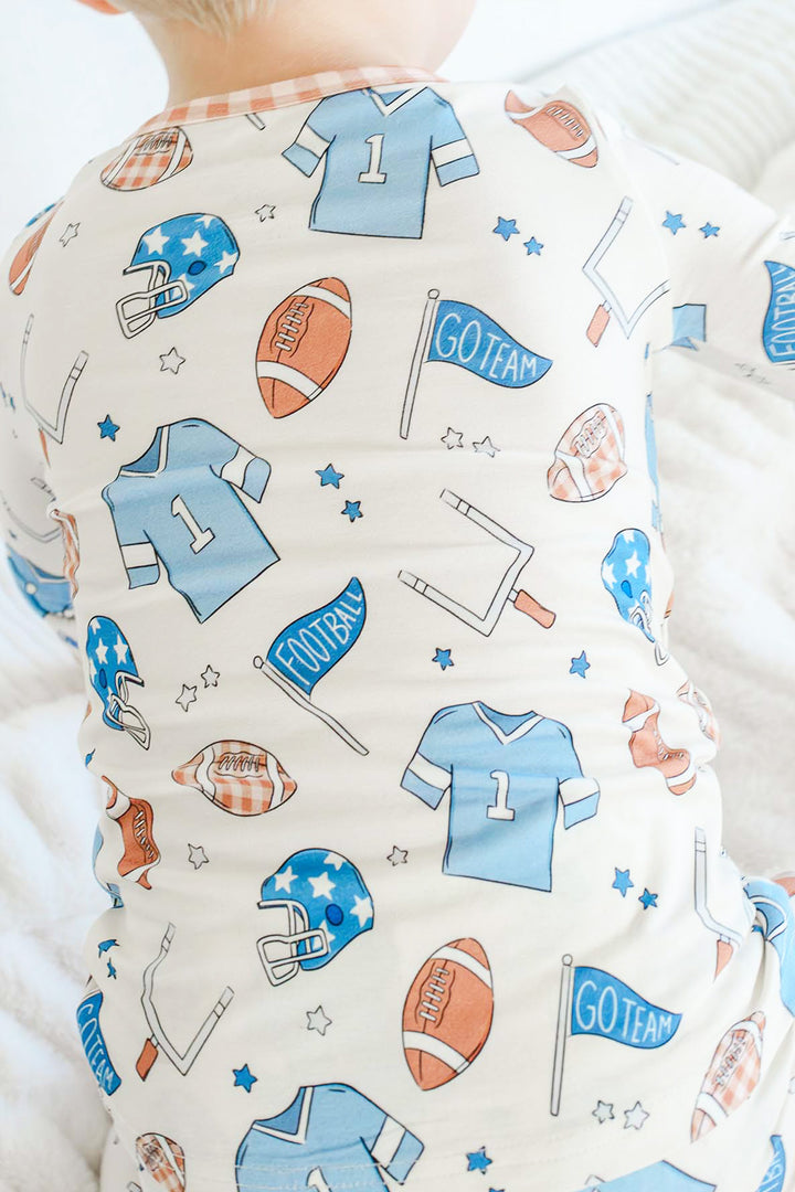 Back view of a little boy wearing the Caden Lane blue huddles and cuddles two piece pajama set.