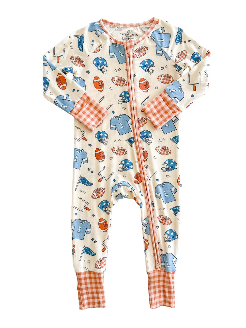 A baby long-sleeve footless one-piece sleeper with a sports-themed print of blue helmets, orange footballs, and white tennis rackets on a cream background. It features orange and white gingham cuffs and a matching orange zipper trim.