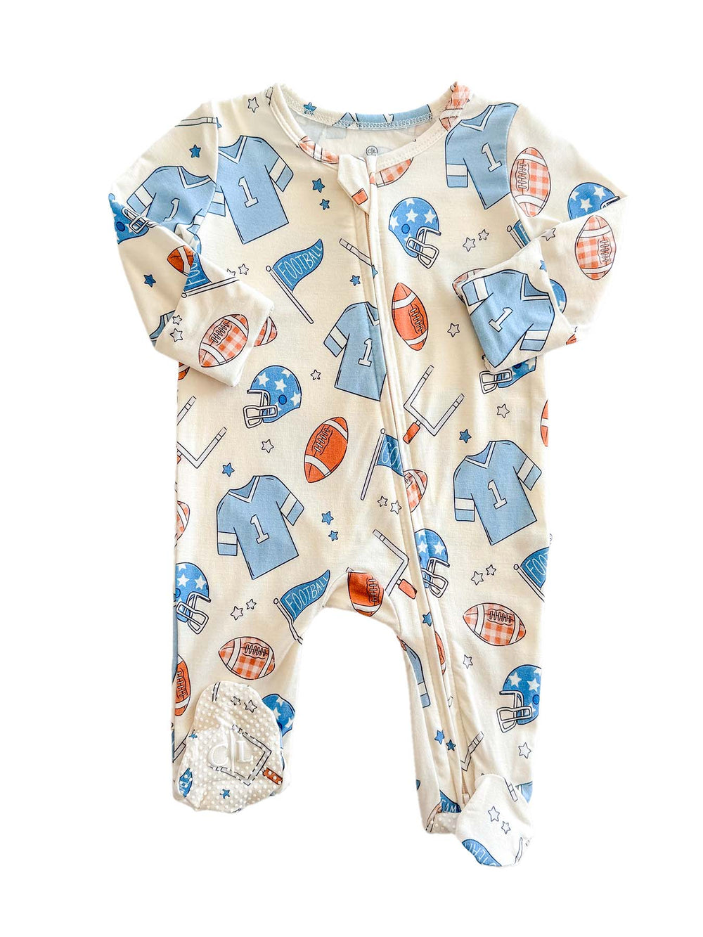 A baby footed sleeper with an all-over sports-themed print on a cream background. The pattern features light blue jerseys, red and orange footballs, blue helmets, and small stars.