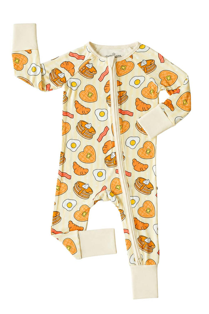 Caden Lane zip footie pajama, flat lay, front view showing zipper and breakfast-themed print