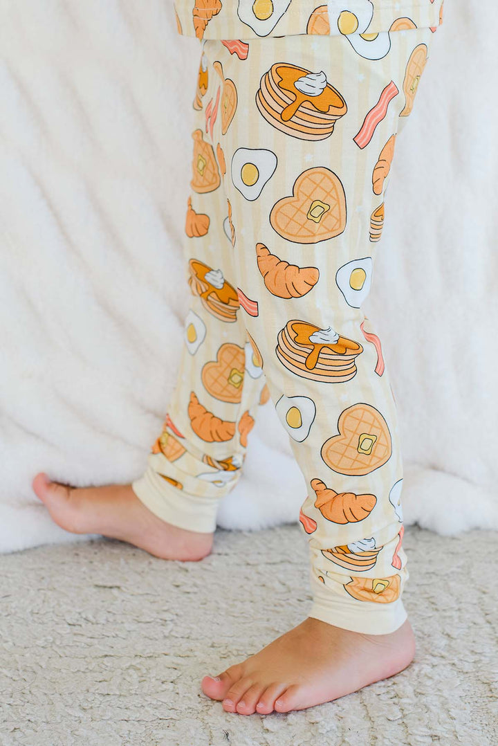 Close-up of child's legs in Caden Lane I Love You A Brunch pajama pants – pancake, waffle, egg and bacon print