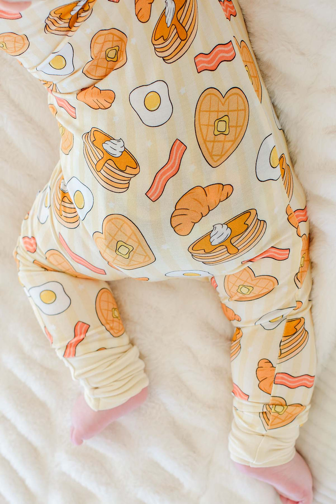 Close-up of baby crawling in Caden Lane zip footie pajama, showing heart-shaped waffle and pancake print
