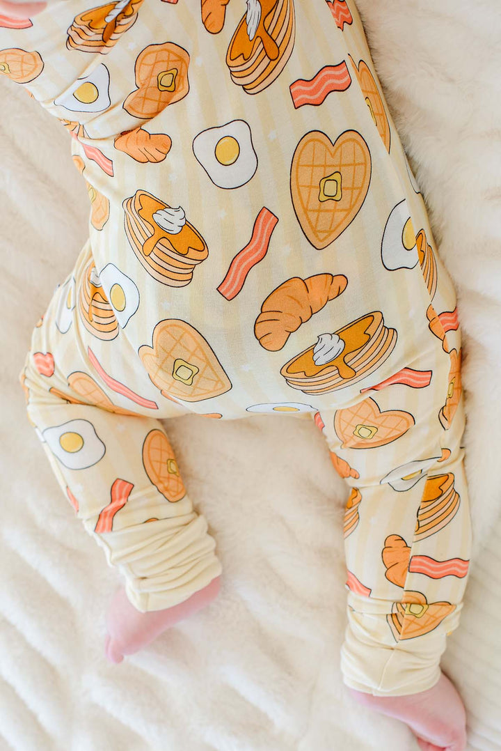 Close-up of baby crawling in Caden Lane zip footie pajama, showing heart-shaped waffle and pancake print