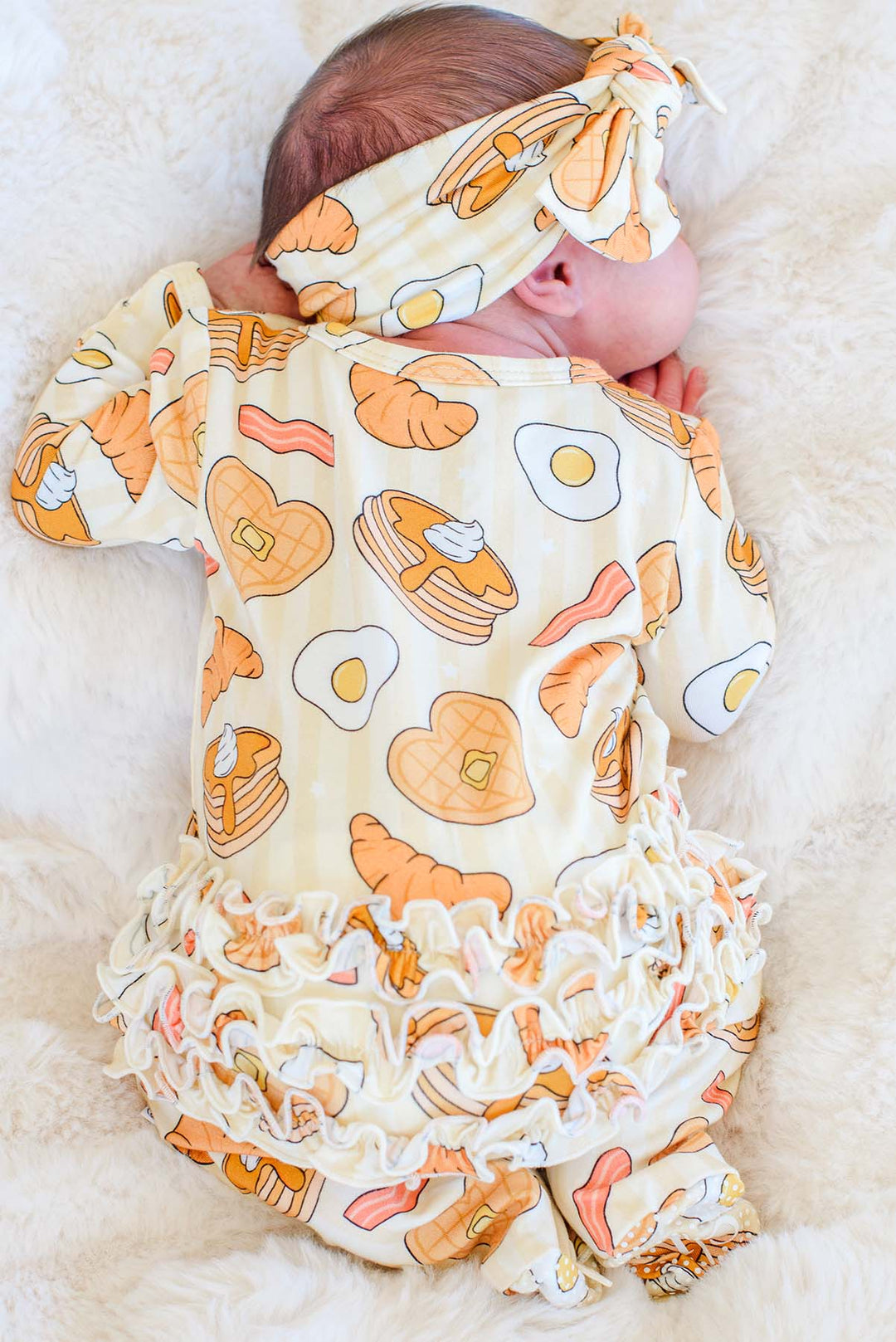 Back view of newborn in Caden Lane I Love You A Brunch ruffle footie and headband, showing ruffle bottom detail