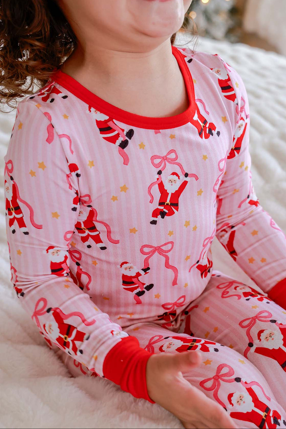 Close-up of the Caden Lane Jolly Ribbons Christmas Bamboo Two-Piece Pajama Set showcasing festive Santa, ribbon bow print, and ultra-soft bamboo fabric.