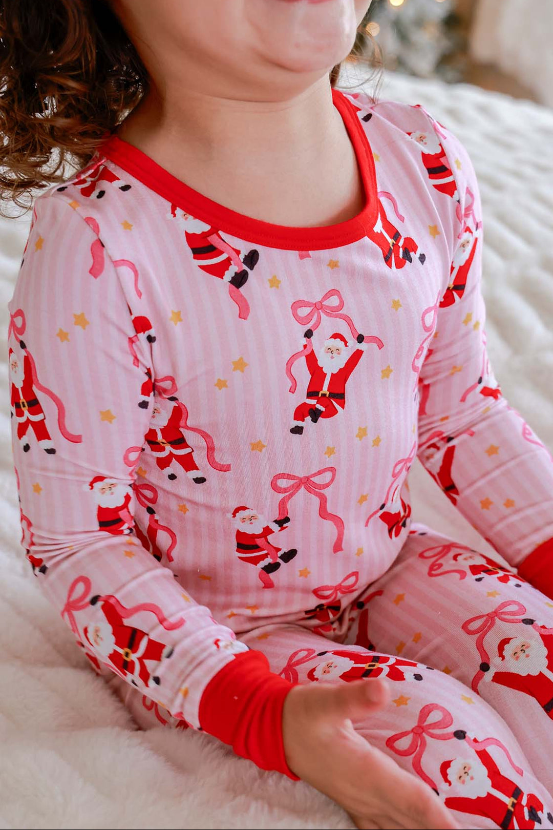 Close-up of the Caden Lane Jolly Ribbons Christmas Bamboo Two-Piece Pajama Set showcasing festive Santa, ribbon bow print, and ultra-soft bamboo fabric.
