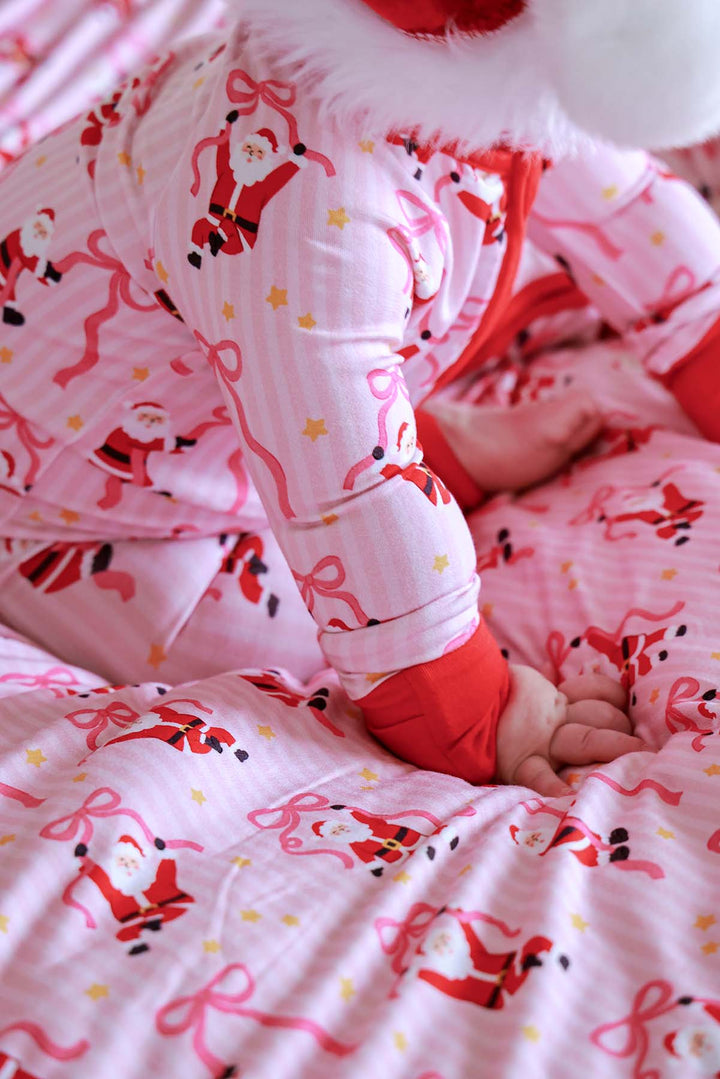 Close-up of the Caden Lane Jolly Ribbons Bamboo Convertible Zip Romper highlighting the soft bamboo fabric, holiday Santa print, ribbon bows, and fold-over cuffs.