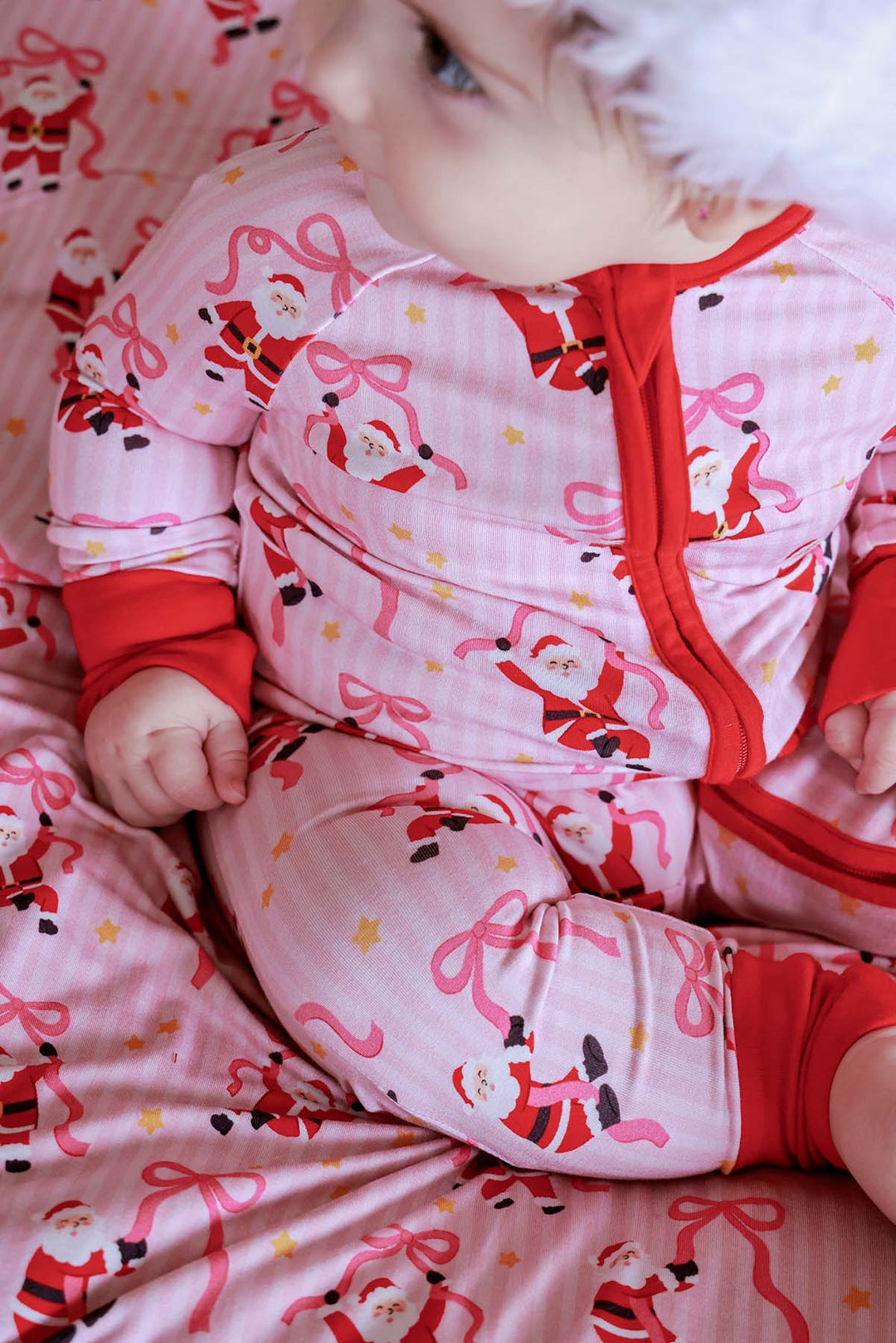 Close-up of the Caden Lane Jolly Ribbons Christmas Bamboo Convertible Zip Romper showcasing the festive Santa print, ribbon bows, and buttery-soft bamboo fabric.