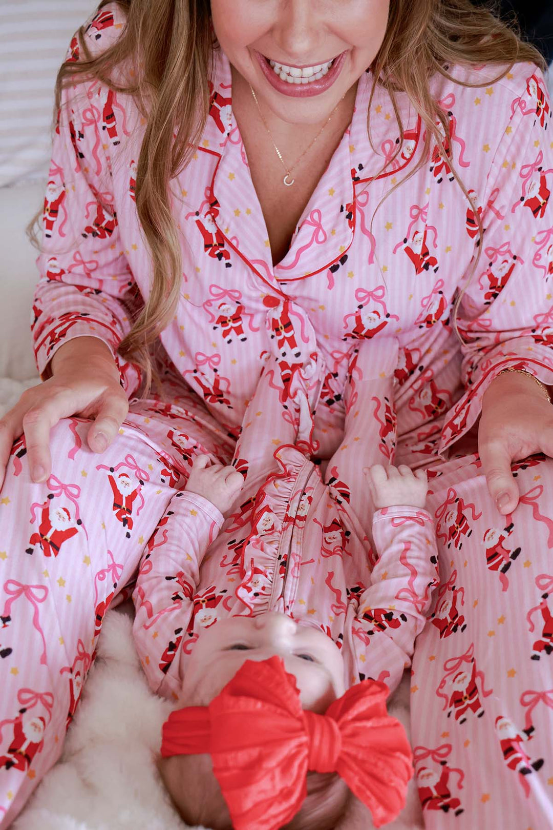 Baby wearing the Caden Lane Jolly Ribbons Christmas Zipper Ruffle Footie while matching with mom in coordinating Caden Lane holiday bamboo pajamas.