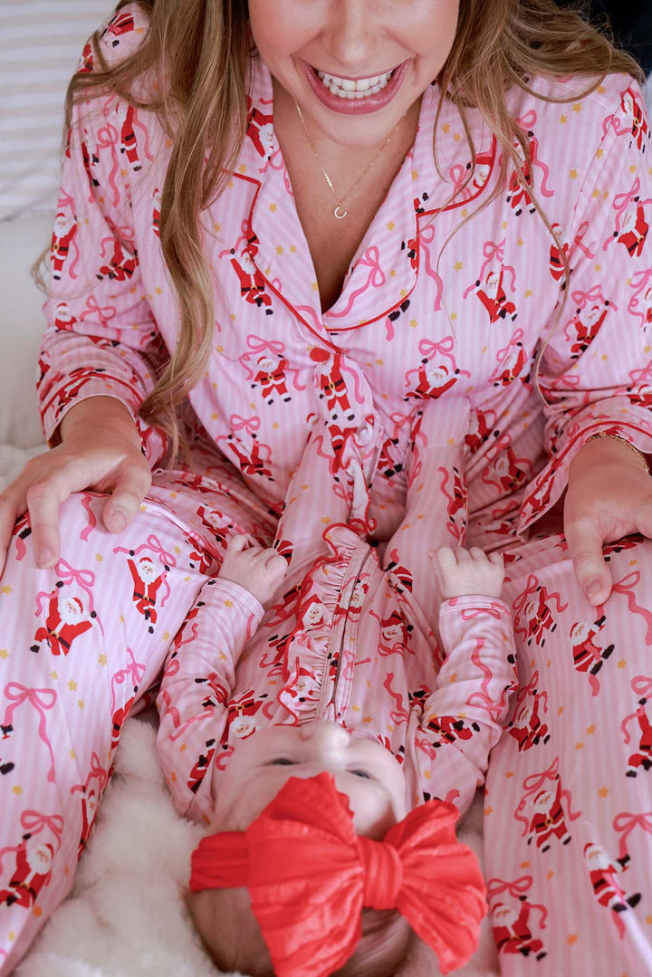 Baby wearing the Caden Lane Jolly Ribbons Christmas Zipper Ruffle Footie while matching with mom in coordinating Caden Lane holiday bamboo pajamas.