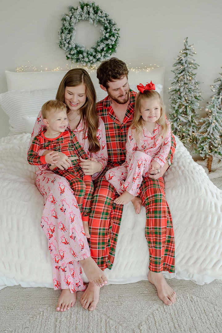 Family wearing matching Caden Lane Christmas pajamas featuring the Jolly Ribbons print for mom and daughter with coordinating Plaid Tidings pajamas for dad and son.