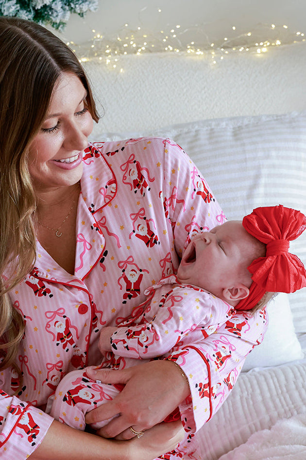 Mother cuddling baby in the Caden Lane Jolly Ribbons Christmas Zipper Ruffle Footie, showcasing matching holiday bamboo pajamas for the sweetest Christmas moments.