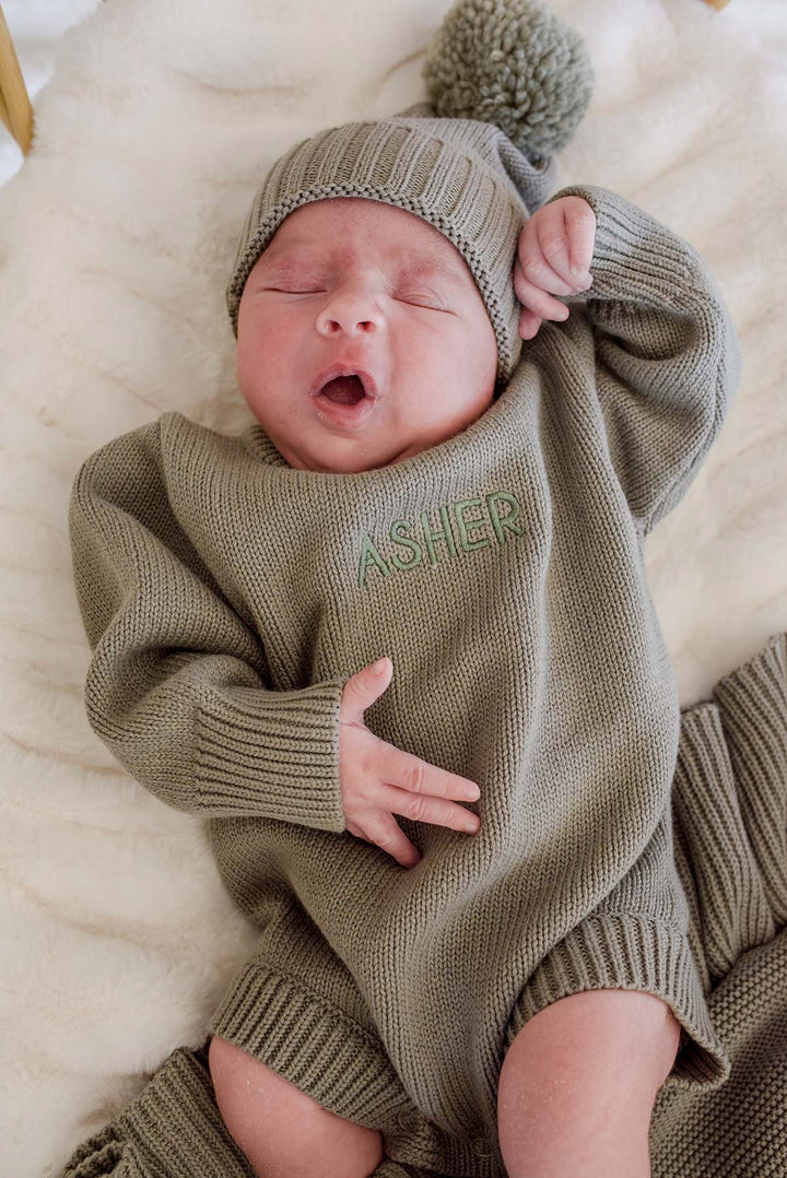 Newborn wearing Caden Lane personalized smoke knit bubble romper and hat embroidered with the name Asher