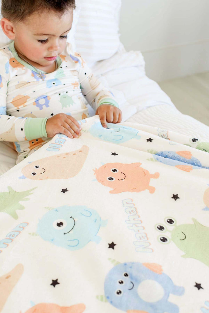 Little boy holding a personalzied Caden Lane Mini Monster minky blanket. 