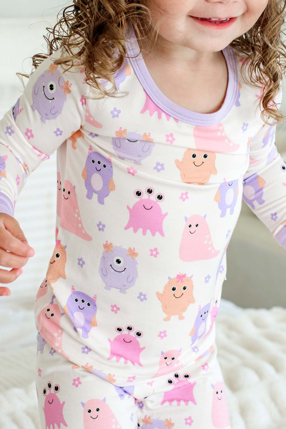 Close-up of a toddler's torso and shoulders showing the neckline and print detail of a Caden Lane Little Monsters two-piece pajama set